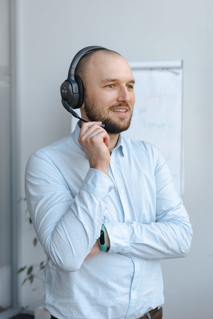 Friendly call center agent wearing headphones, engaged in conversation indoors.